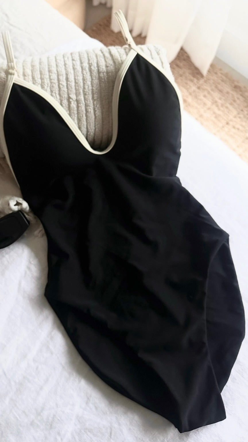 Black swimsuit with beige straps on a textured surface