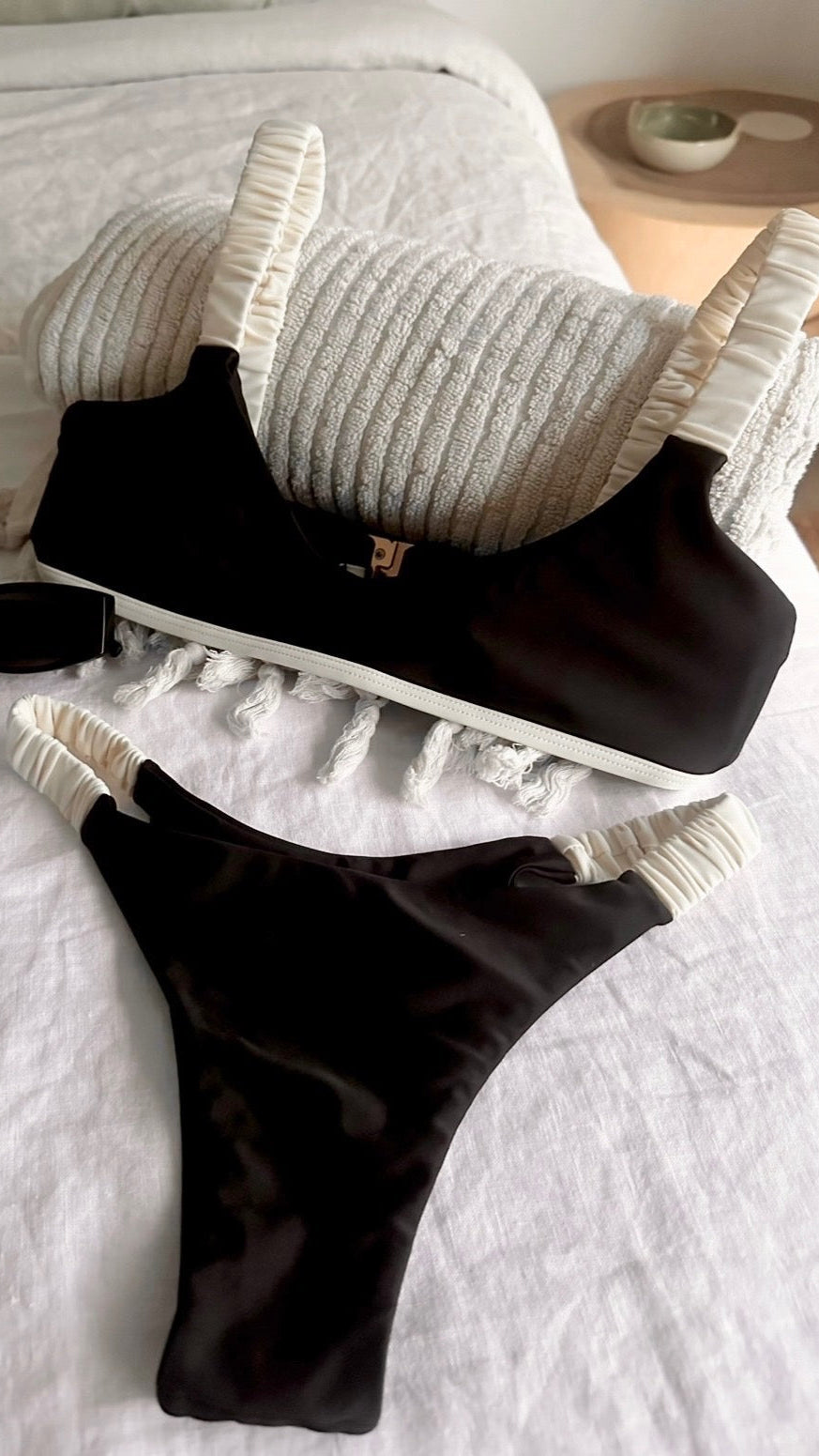 Black bikini set with white trim on a bed