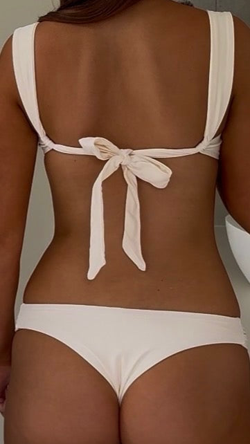 Person wearing a white bikini with a minimal background