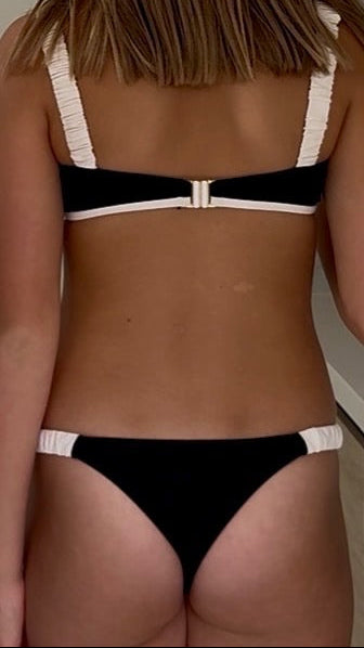 Person wearing a black and white bikini with a neutral background